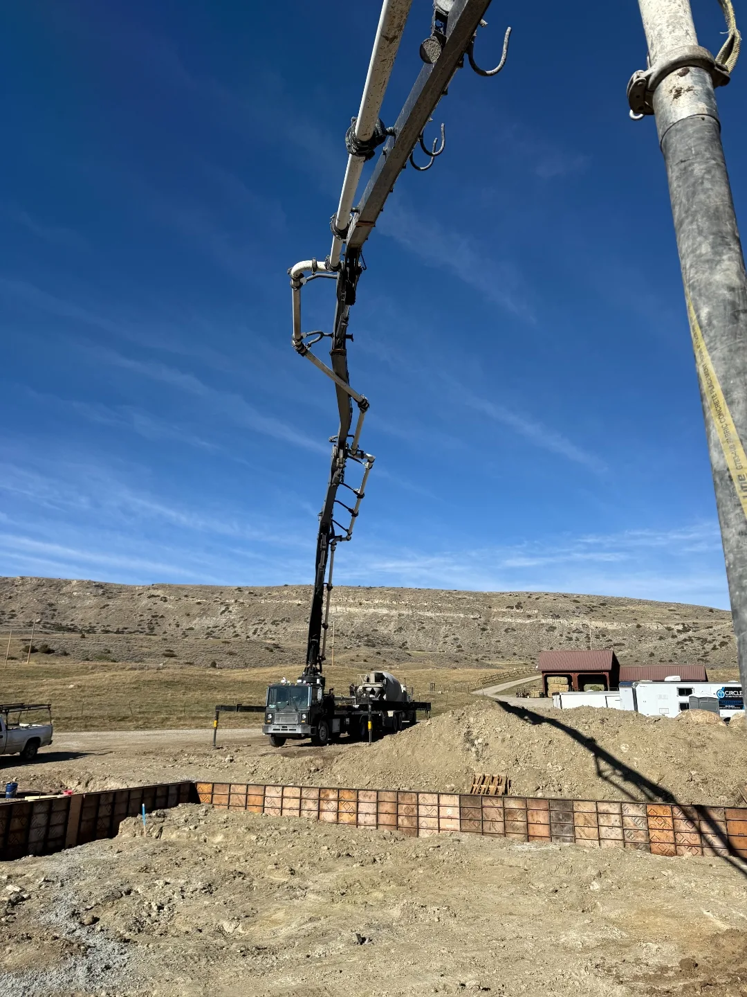 Close view along a concrete pump boom above a rural foundation