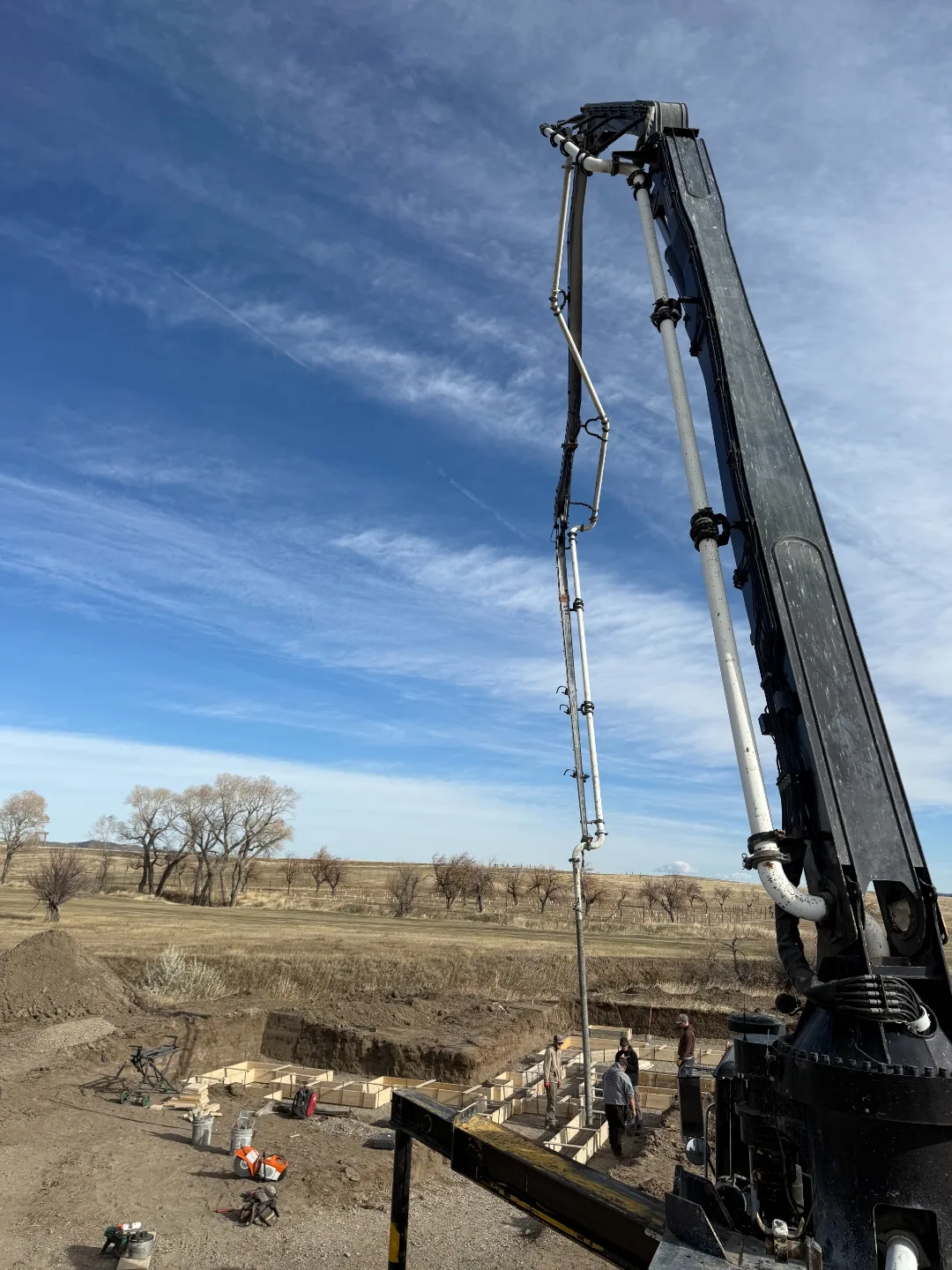 Concrete pump boom positioned above foundation forms