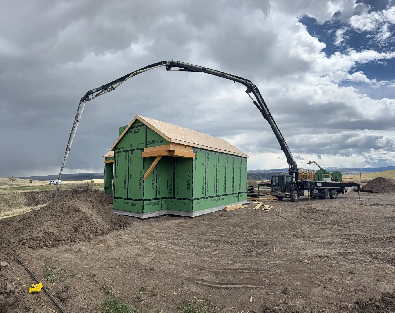 Concrete boom pump reaching over a new building on a rural Montana jobsite