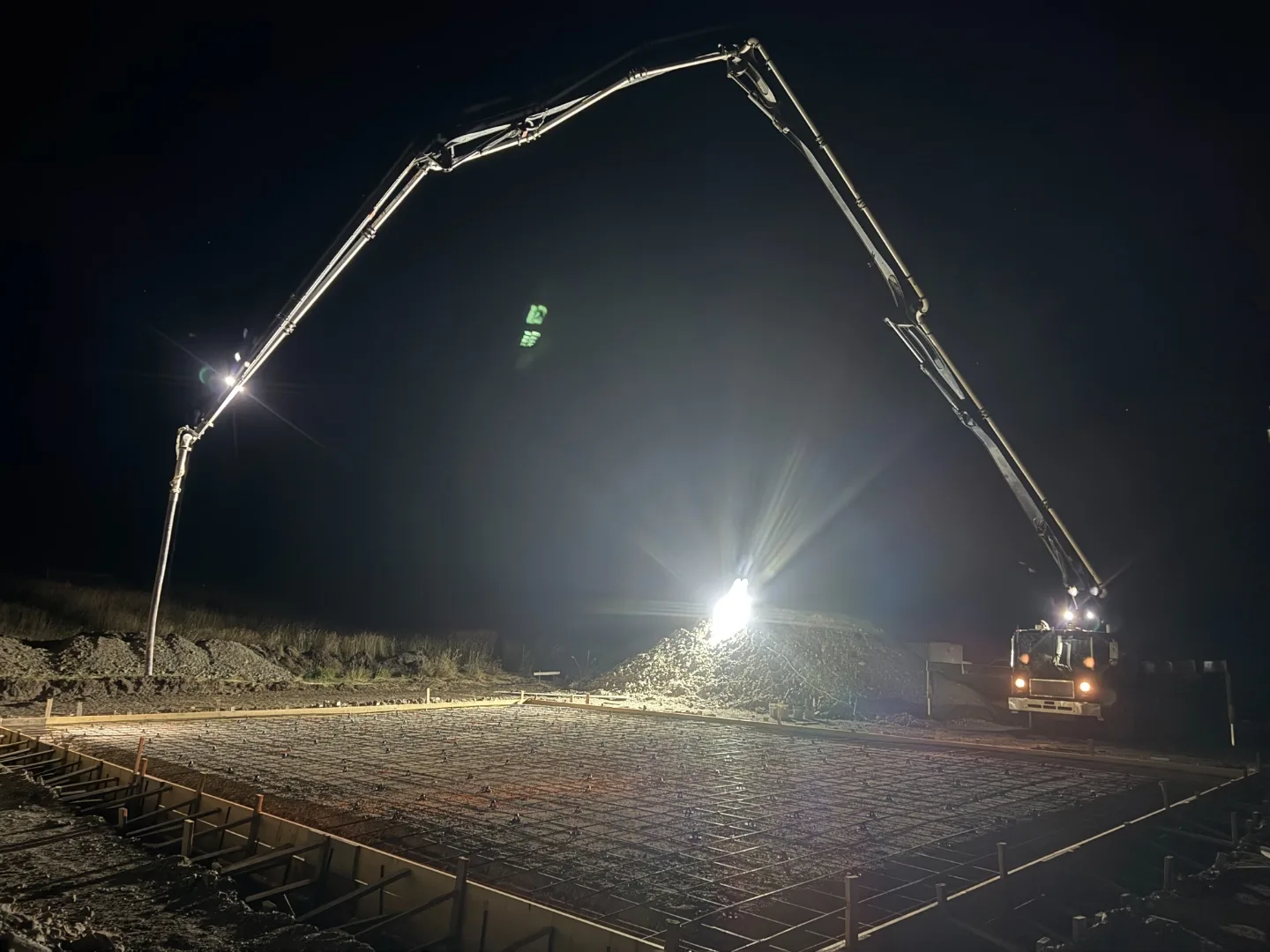 Concrete boom pump working over a reinforced slab at night