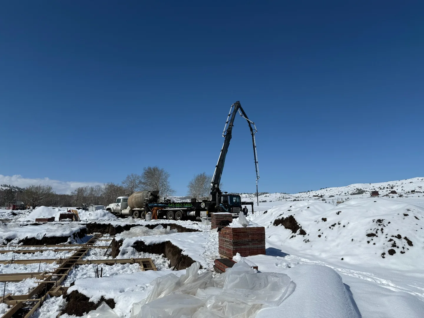 Concrete pump and mixer working at a snow-covered Montana jobsite